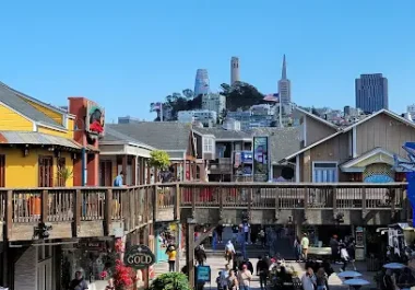 Pier 39 waterfront marketplace in San Francisco with shops and tourists under clear blue sky