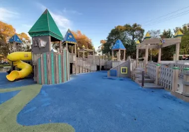 Colorful playground with castle tower, slides, and blue safety surface in Concord
