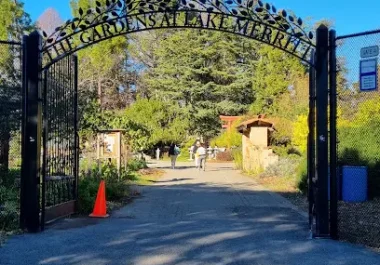 Gardens at Lake Merritt entrance gate in Oakland with tree-lined park pathway